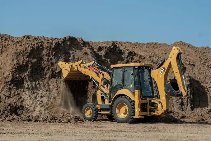 Mighty Minds backhoe loader working at a soil stockpile